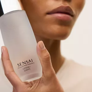 Close up of person holding Cellular Performance Lotion 1 (Light) next to their face with their hand